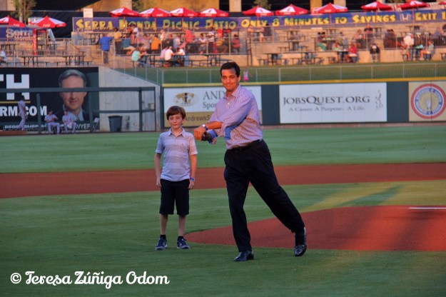 Mike Suco, throws out the ceremonial first pitch as his son watches beside him.