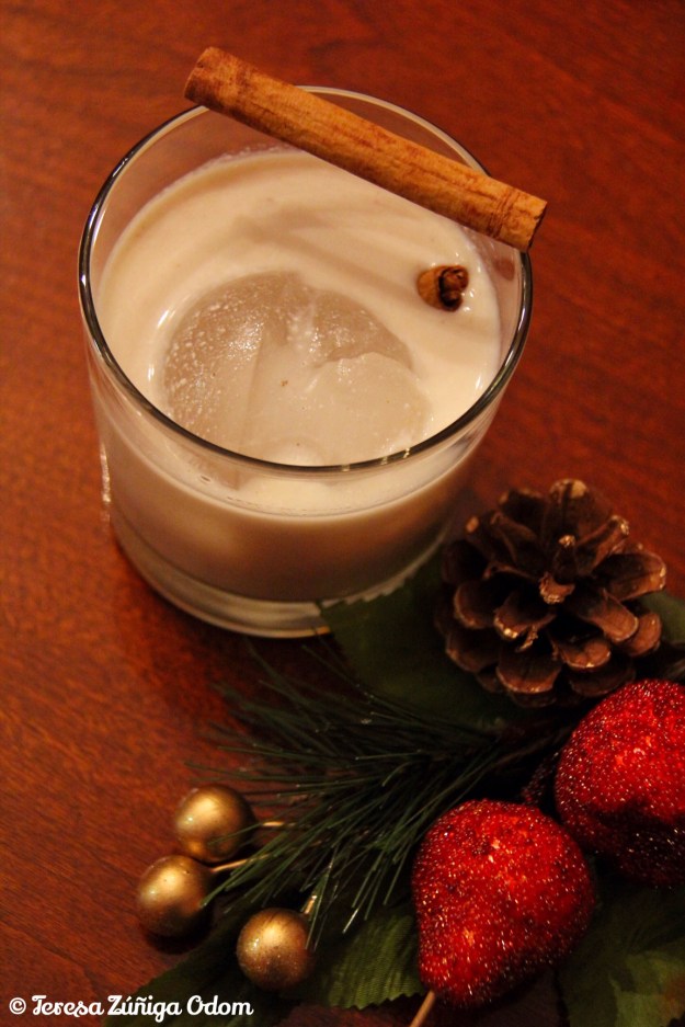 A glass of coquito garnished with two cinnamon sticks! Best served over ice and sipped in front of a Christmas tree!